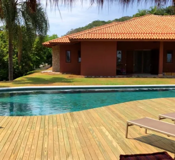 Deck de madeira contornando a borda de uma piscina residencial
