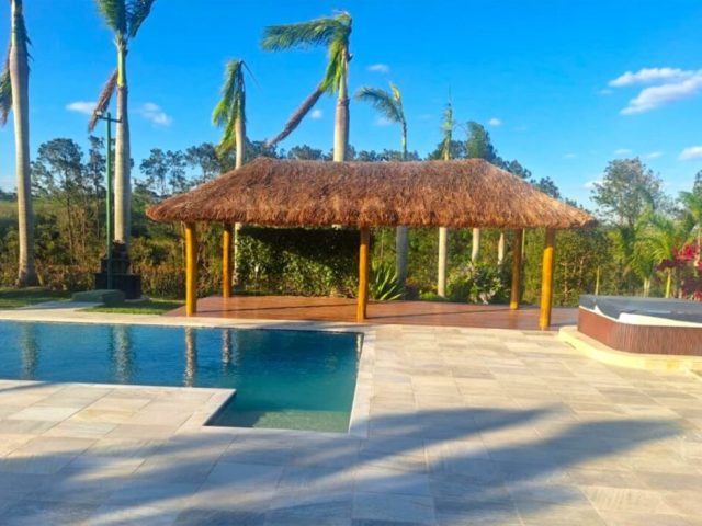 Quiosque de madeira e cobertura em sapê com piscina