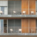 Um Edificio Alto Com Varandas E Cadeiras Nas Varandas 1PdHMTELbxE