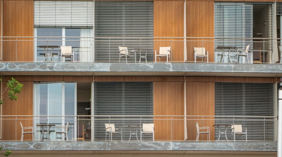Um Edificio Alto Com Varandas E Cadeiras Nas Varandas 1PdHMTELbxE