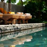 Uma Fileira De Cadeiras De Madeira Sentadas Ao Lado De Uma Piscina Y_bjlQYfQ_0