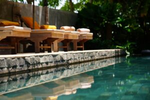 Uma Fileira De Cadeiras De Madeira Sentadas Ao Lado De Uma Piscina Y_bjlQYfQ_0