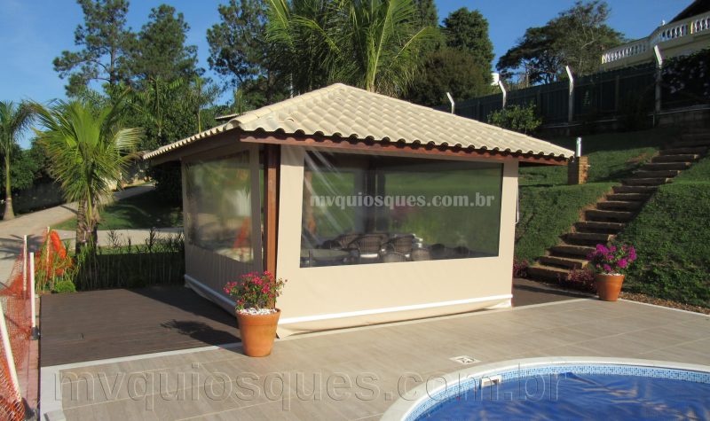 Um quiosque de telha á beira da piscina com toldos para proteger dos tempos chuvosos.